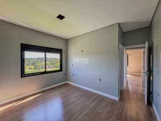 Sala de estar com piso de madeira e vista para a paisagem verde.