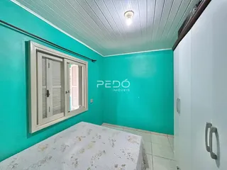 Quarto com paredes turquesa e janela com venezianas brancas.