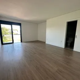 Sala de estar com piso de madeira e portas de vidro que dão acesso ao exterior.