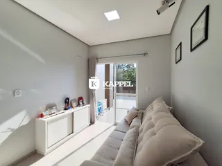 Uma sala de estar clara com sofá e móveis brancos.