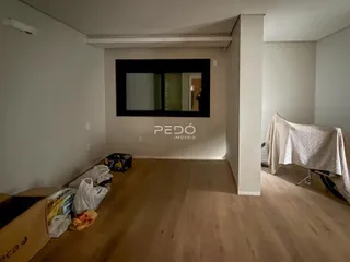 Vista interna de um cômodo com piso de madeira e moldura escura.