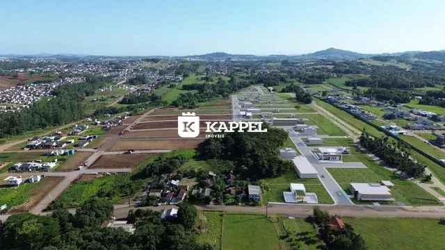 Vista aérea de um loteamento com áreas verdes e construções dispersas.