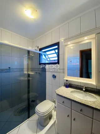 Foto de um banheiro com revestimento cerâmico e box de vidro.