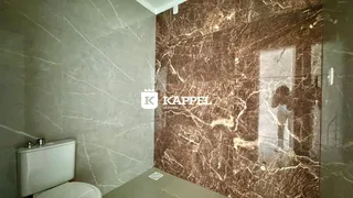 Foto interna de um banheiro com revestimento de mármore marrom nas paredes.