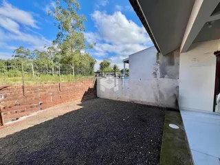 Vista externa do quintal com muro de tijolos e vegetação.