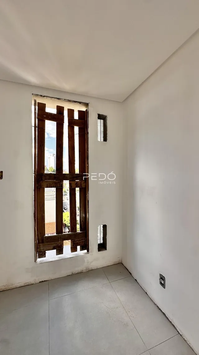 Vista interna de um cômodo com moldura de madeira e piso de cerâmica.