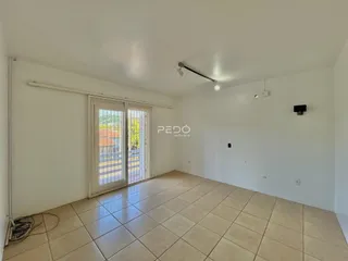 Sala de estar com piso de cerâmica e portas de vidro que dão acesso ao exterior.