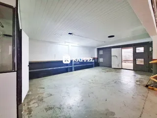 Vista interna de um ambiente amplo com piso de concreto e teto de painéis brancos.