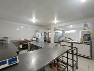Vista ampla de uma cozinha industrial moderna com bancadas de aço inoxidável.