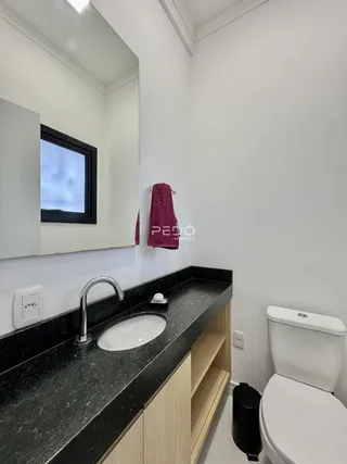 Banheiro com bancada escura e armário de madeira.