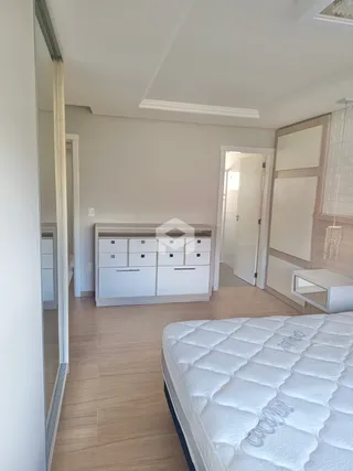 Quarto com piso de madeira clara e cabeceira de cama branca.