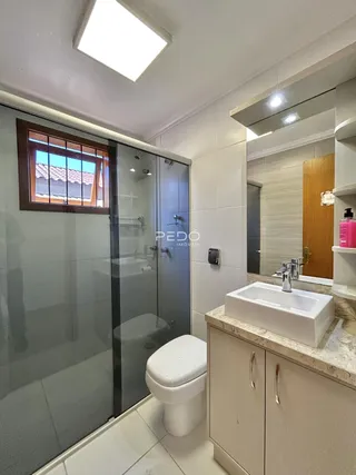 Banheiro com box de vidro e bancada de mármore claro.