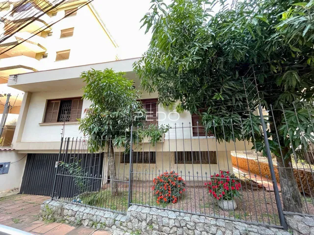 Fachada de uma residência com cerca e vegetação na frente.
