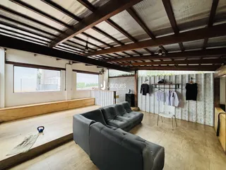 Sala de estar ampla com piso de madeira e teto de vigas expostas.