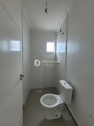 Hall de corredor interno com porta e vaso sanitário branco.