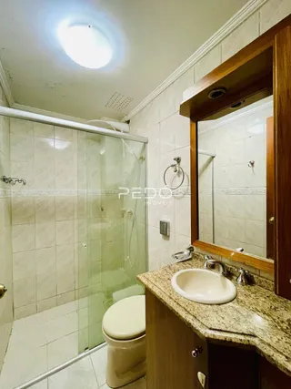 Foto de um banheiro com revestimento cerâmico e box de vidro.