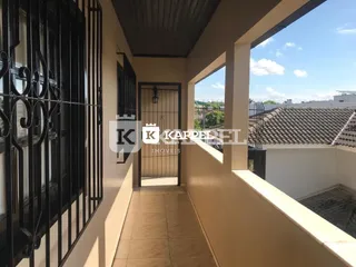 Corredor externo com grades de ferro escuro em uma propriedade em Lajeado.