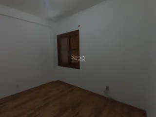 Foto de um cômodo interno com piso de madeira e paredes brancas.
