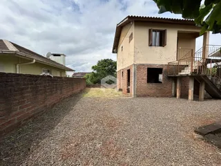 Vista externa de uma casa em Lajeado, Brasil, com muro de tijolos e quintal de cascalho.