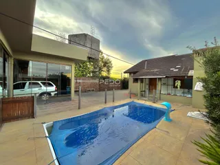 Foto da fachada de uma casa com piscina no quintal.