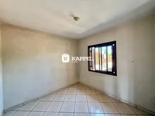 Um corredor com piso de cerâmica e uma janela na parede.