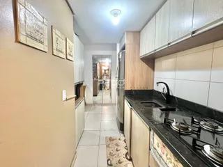 Vista de um corredor que leva a uma cozinha com armários e bancadas.