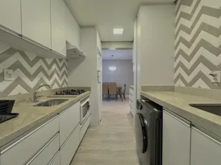 Cozinha moderna com armários brancos e bancadas claras.