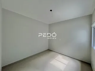 Vista interna de um ambiente vazio com paredes brancas e piso claro.