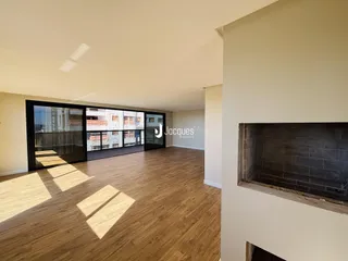 Sala de estar ampla com piso de madeira e grandes portas de vidro.