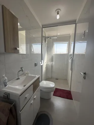 Foto de um banheiro moderno com revestimento branco e detalhes em madeira.