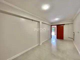 Hall de entrada com piso claro e paredes brancas.