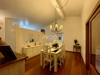 Interior de uma sala de jantar com piso de madeira e móveis brancos.
