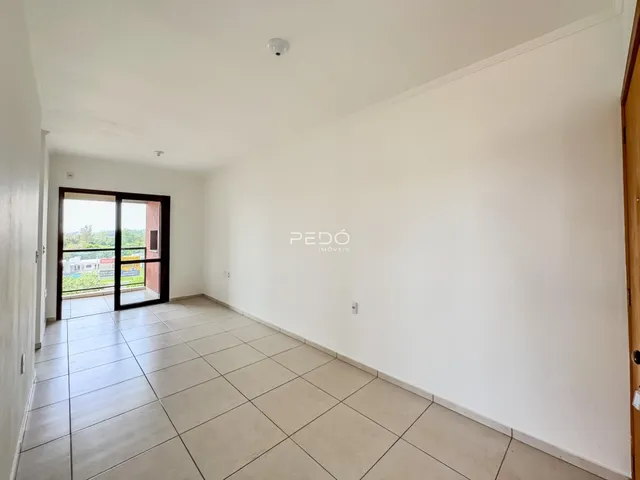 Interior de uma sala com piso de cerâmica e porta de vidro abrindo para o exterior.