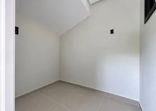 Vista de um canto interno com paredes brancas e piso de cerâmica.