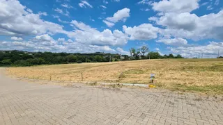 Vista de um campo aberto com vegetação e céu azul.