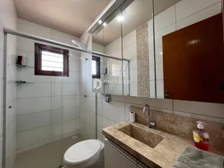 Foto interna de um banheiro com box de vidro e pia de granito.