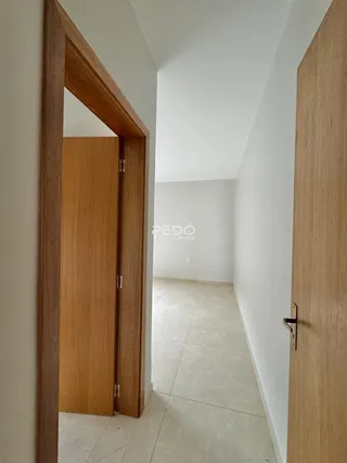 Hall de entrada com portas de madeira e piso claro.