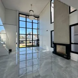 Ambiente interno amplo com piso de porcelanato e grandes janelas com vista urbana.