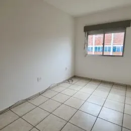 Vista interna de um cômodo com piso de cerâmica e janela.