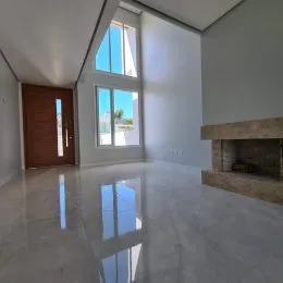 Ambiente interno amplo com piso claro e grandes janelas.