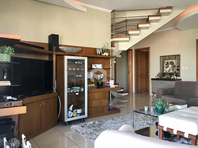 Sala de estar com decoração de madeira e escadaria em um apartamento em Lajeado.