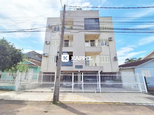 Fachada de um prédio residencial em Lajeado, Brasil, com portão de segurança branco.
