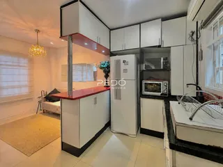 Vista de uma cozinha moderna com armários brancos e bancada vermelha.