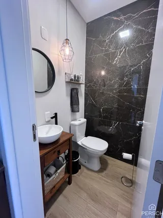 Foto de um banheiro com revestimento de parede em mármore escuro e piso de madeira.