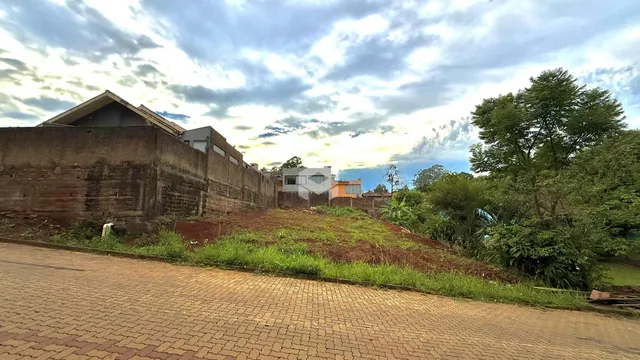 Vista externa de uma propriedade com muro de alvenaria e vegetação ao fundo.