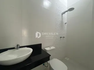 Banheiro com azulejos brancos e bancada escura.