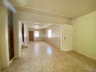 Vista interna de um corredor com piso de cerâmica claro.