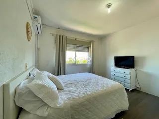 Quarto com cama e janela em ambiente claro.