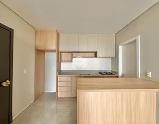 Vista interna de uma cozinha moderna com armários de madeira clara.