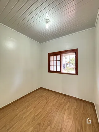 Quarto interno com piso de madeira e janela.